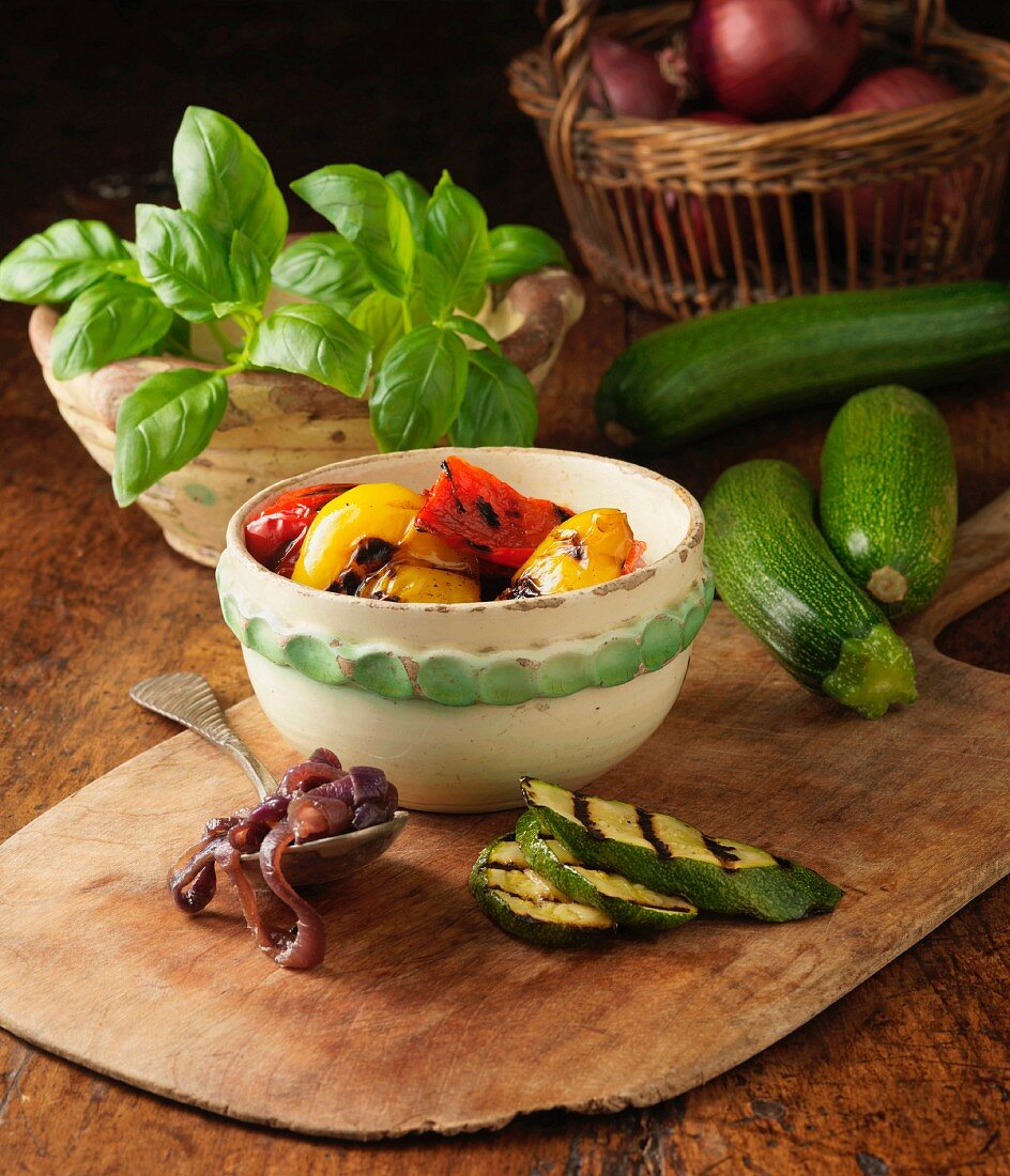 Ingredients for char grilled vegetable and basil pesto pizza on rustic pizza board