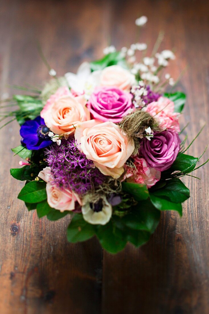 A bouquet of flowers with roses, pinks and anemones