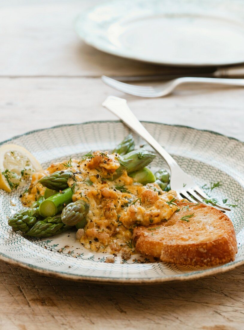 Scrambled egg with crab, served with asparagus and dill