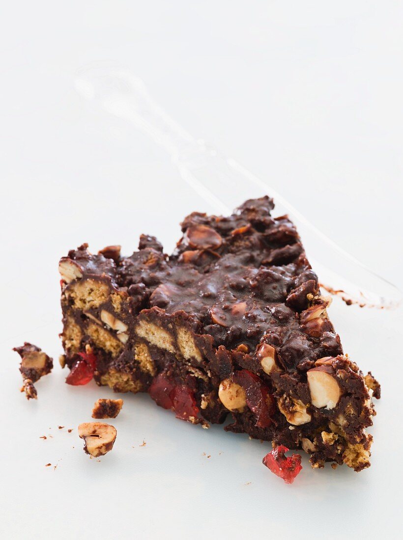 A slice of chocolate biscuit cake with glacé cherries and nuts