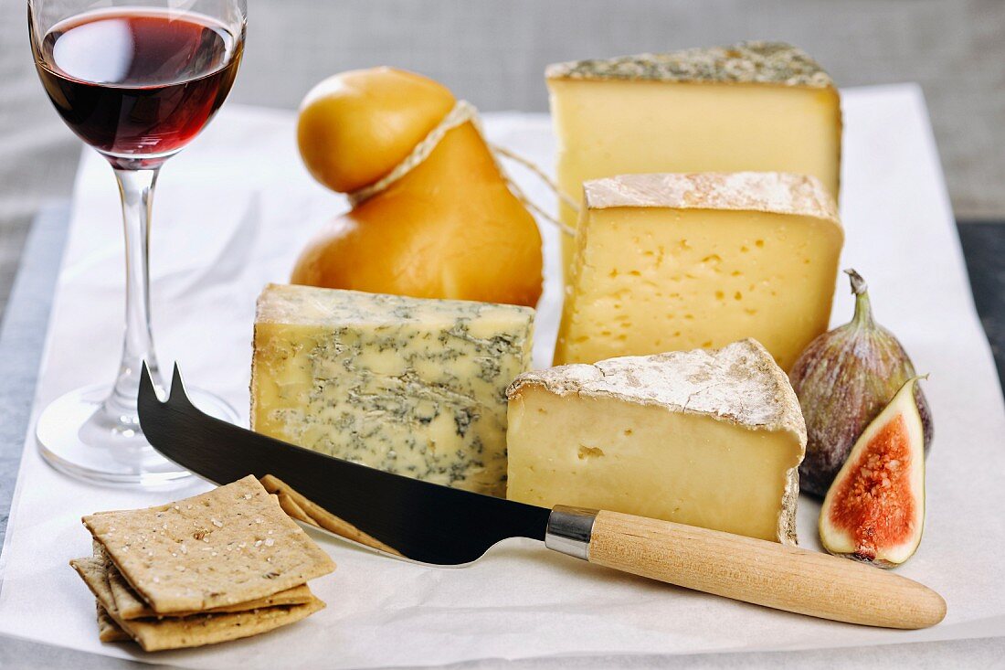 Assorted types of cheese with figs, crackers and a glass of port