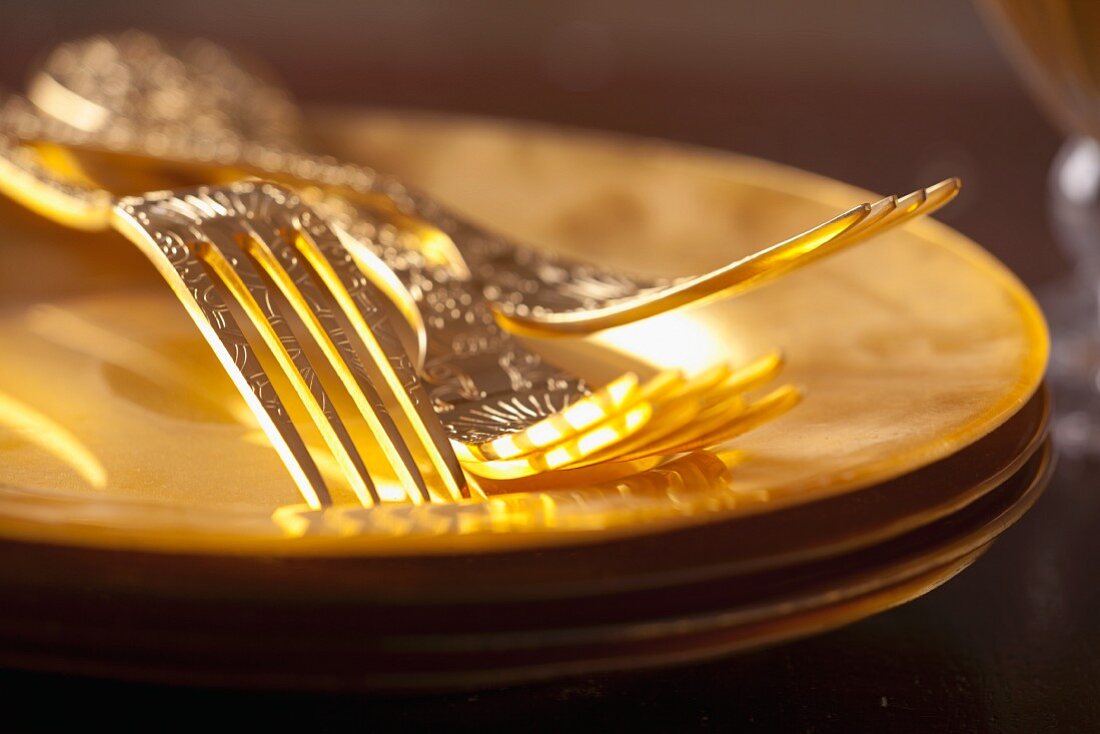 Golden forks on stacked gold plates