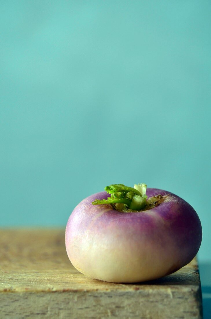 A turnip on a wooden board against a blue background