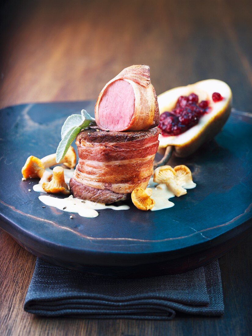 Medallion of venison wrapped in bacon with a cranberry-stuffed pear