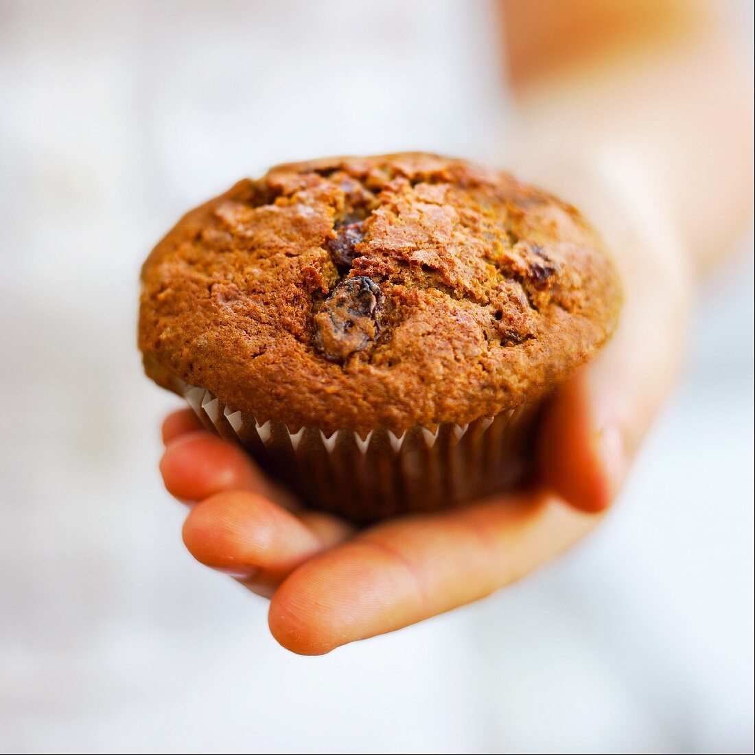 Hand hält einen Rosinenmuffin