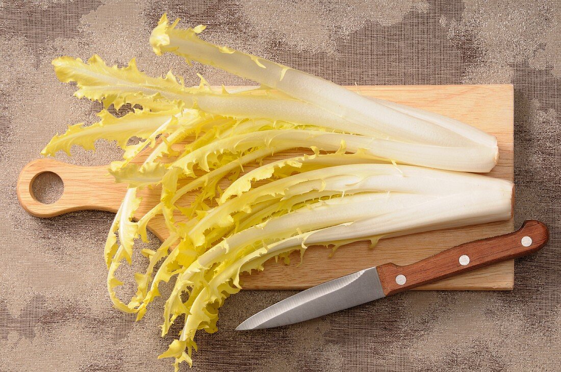 Dandelion leaves on a chopping board with a knife