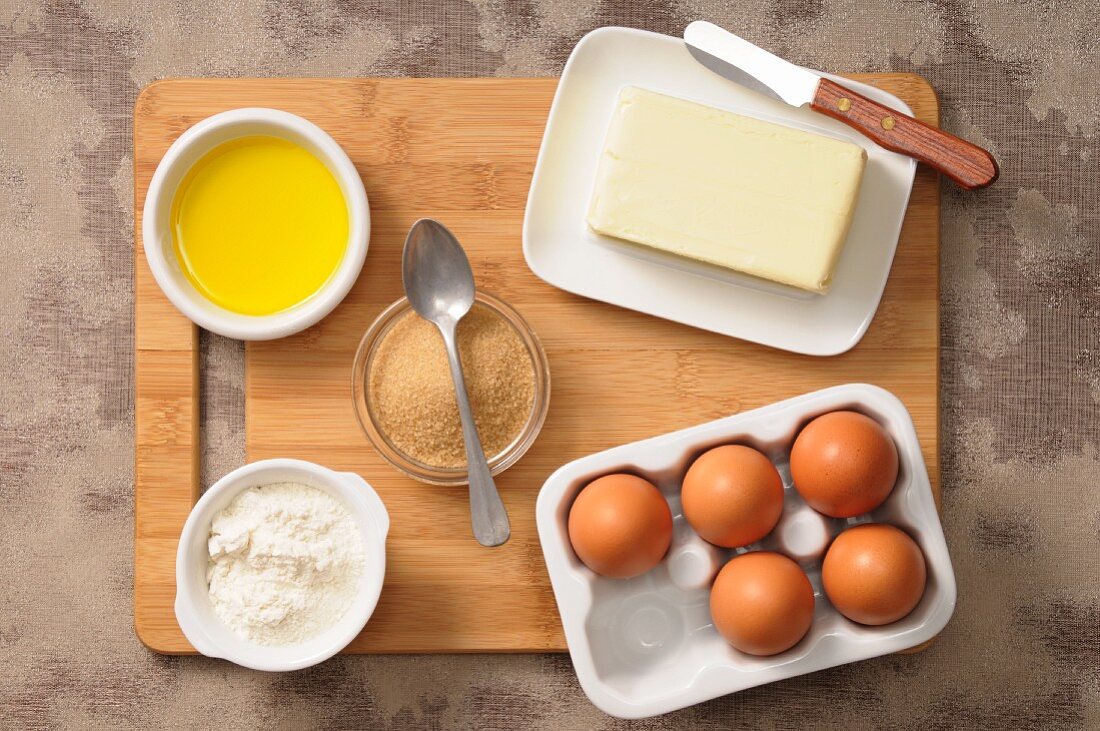 Assorted baking ingredients (eggs, sugar, butter, flour, olive oil)