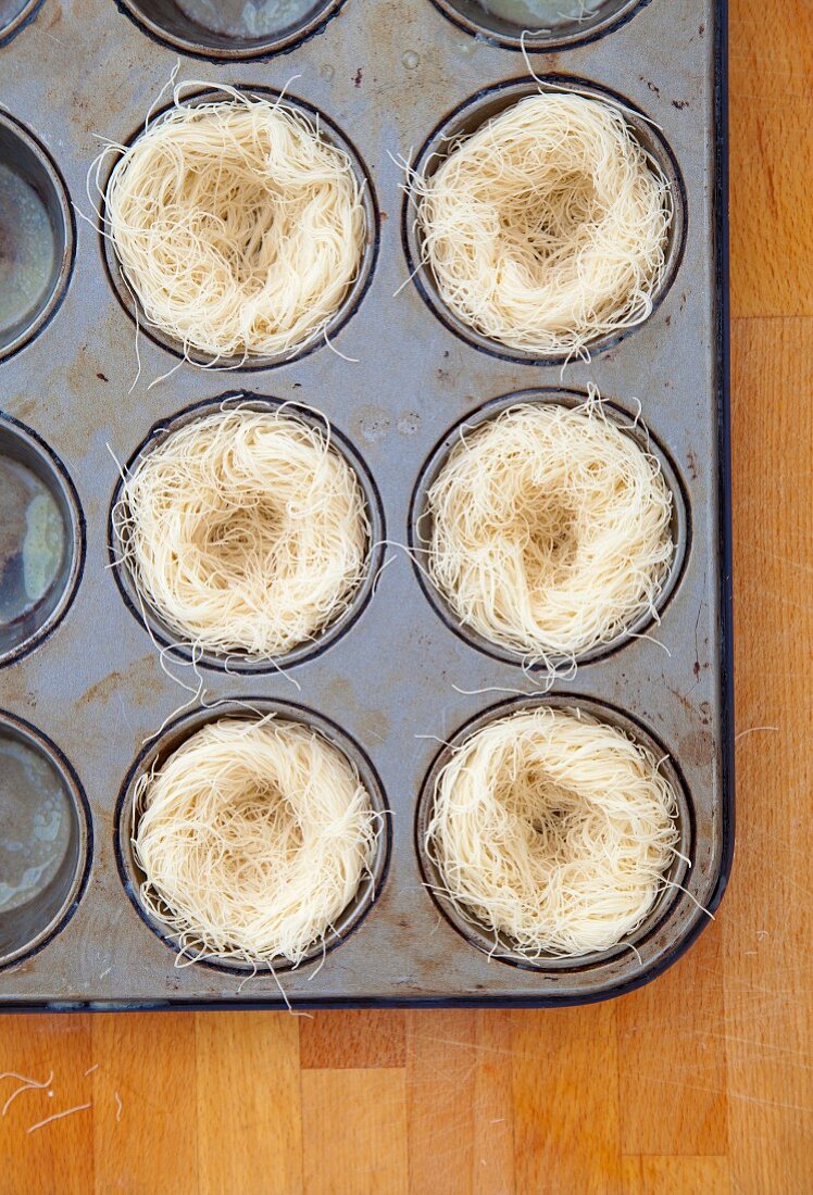 Nests of kadaifi pastry in a muffin tin