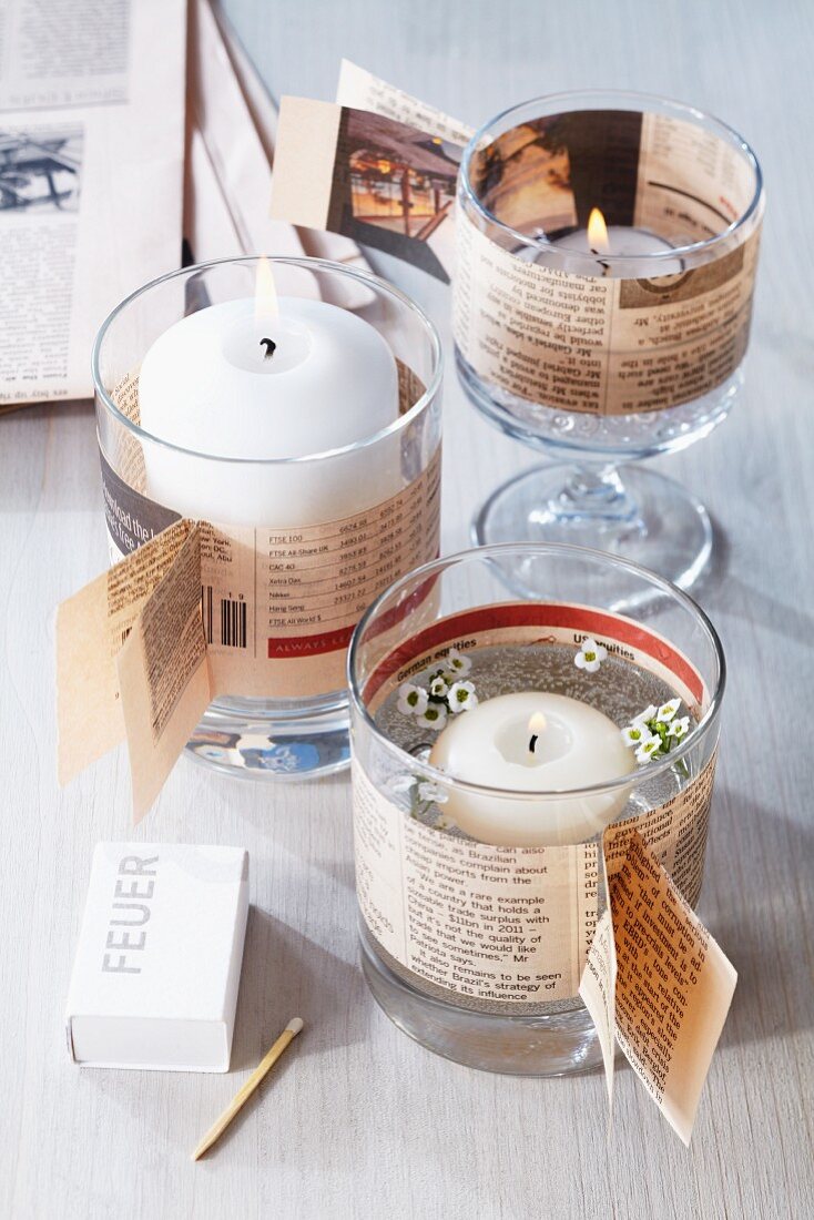 Candle lanterns made from drinking glasses decorated with newspaper