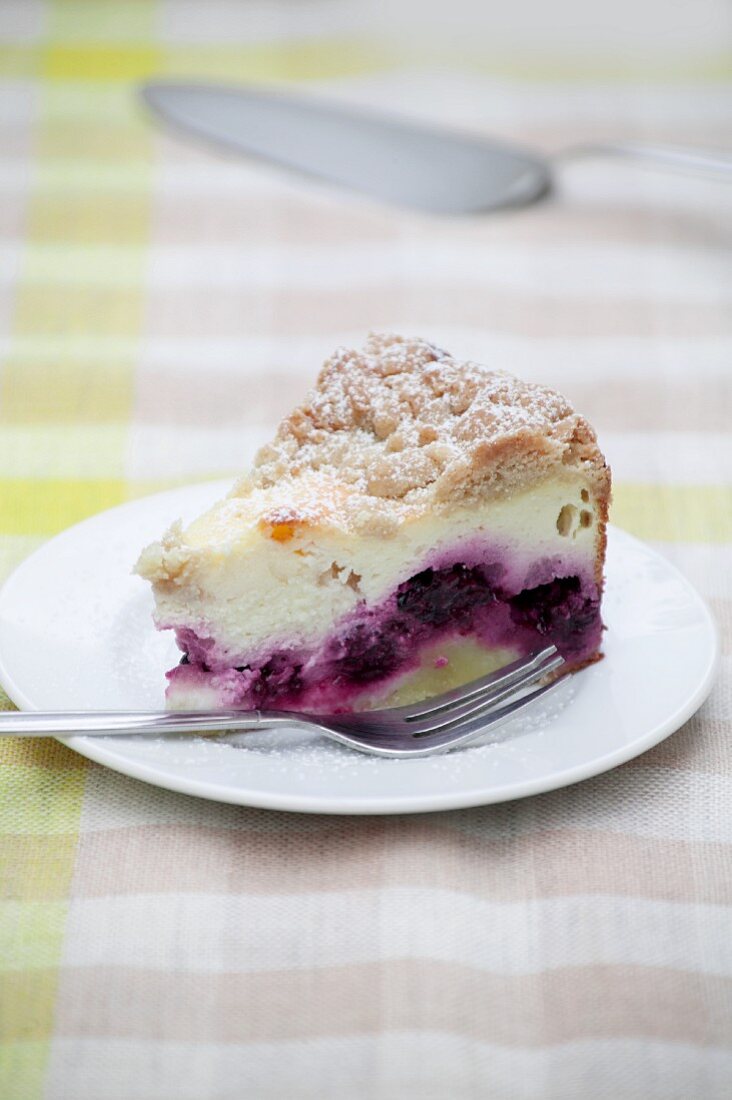 A slice of crumble-topped quark cake with blackberries