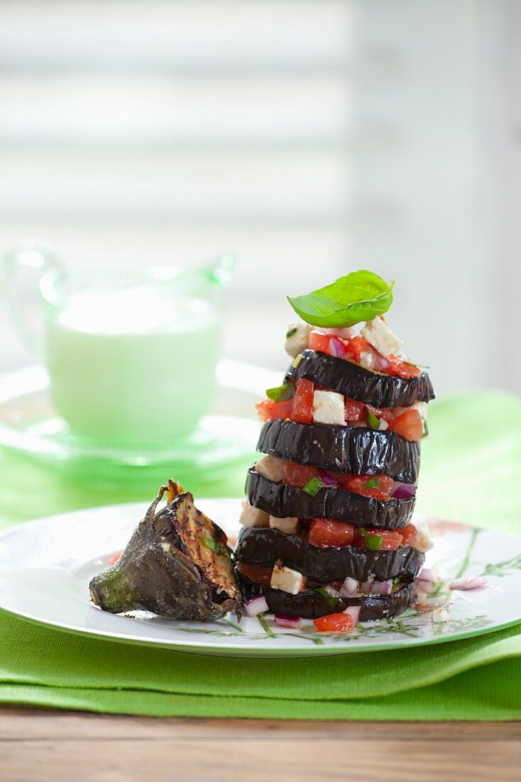 A tower of grilled aubergine slices with tomatoes and feta
