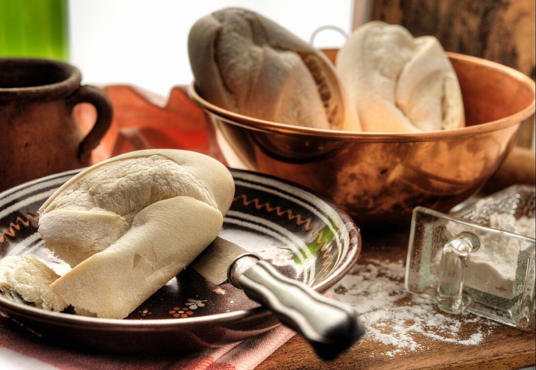 White French bread in a copper bowl and some on a plate