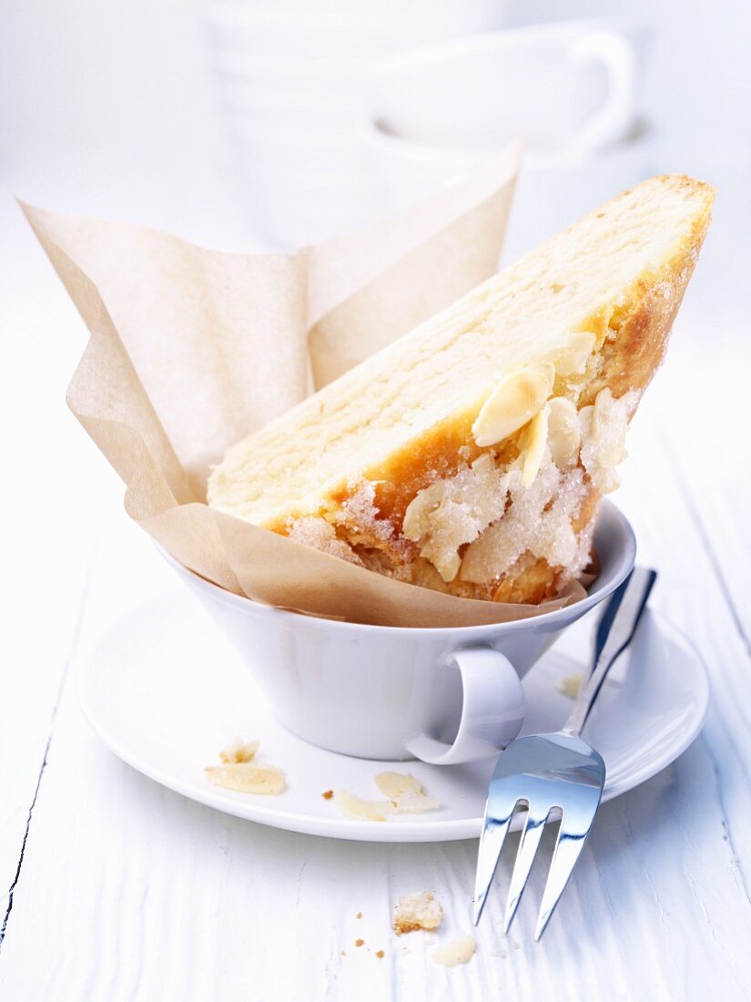 Ein Stück Butterkuchen mit Mandelblättchen in einer Tasse