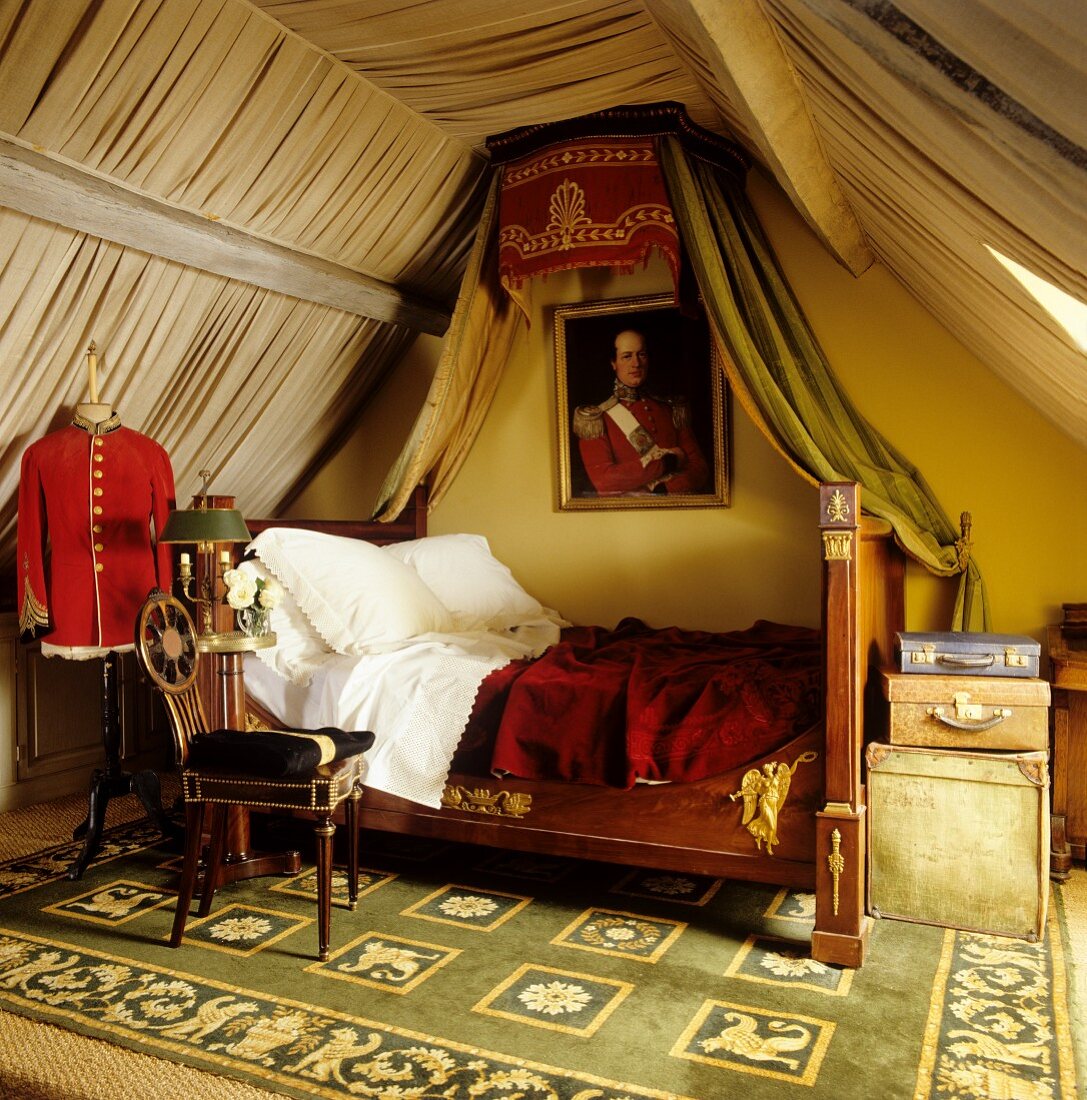 Antique sleigh bed with canopy and walls and ceiling hung with lengths of pale fabric in attic bedroom