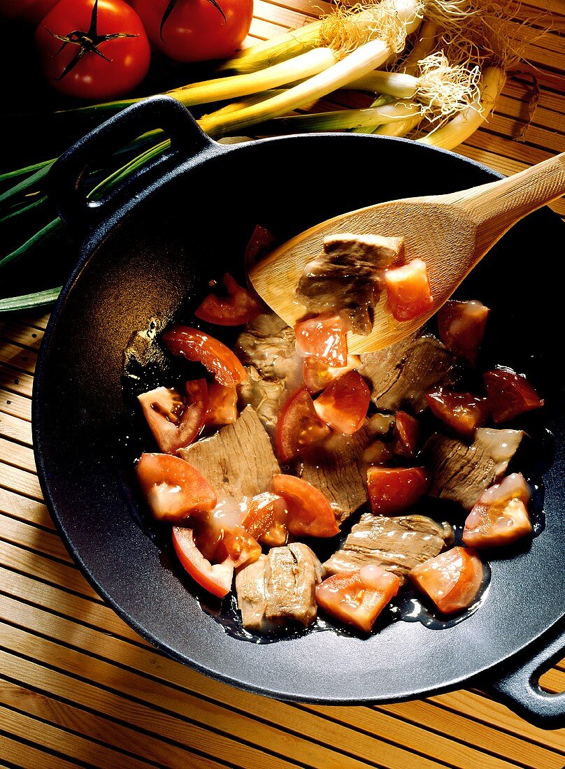Beef and Tomatoes Cooking in a Wok; Spatula