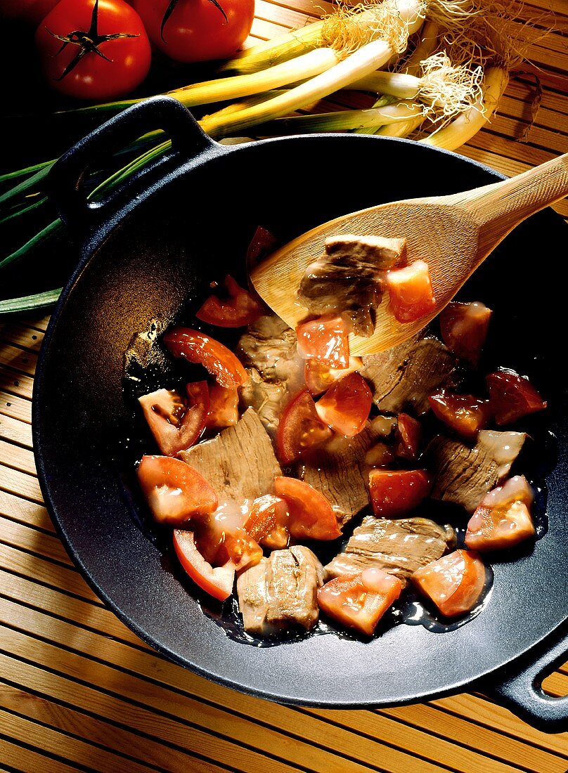 Rindfleisch mit Tomaten im Wok; Deko: Frühlingszwiebeln