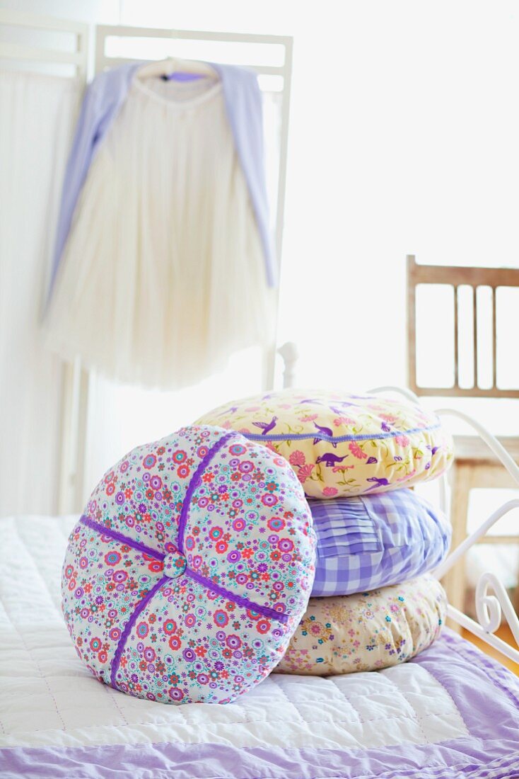 Stack of scatter cushions on bed in bedroom