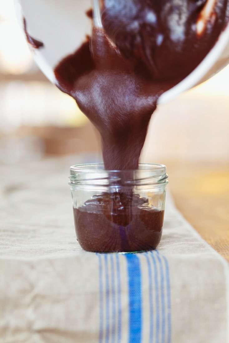 Schokoladen-Haselnuss-Butter in ein Glas gießen