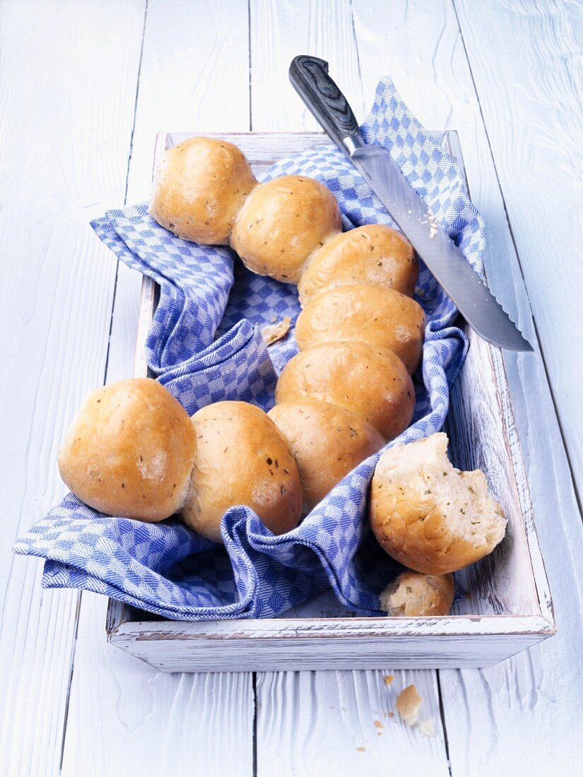 Party bread rolls on a tea towel with a bread knife