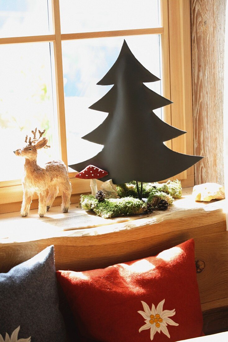 Edelweisskissen und Elchfigur neben stilisiertem Tannenbaum mit Fliegenpilz, Moos und Zapfen