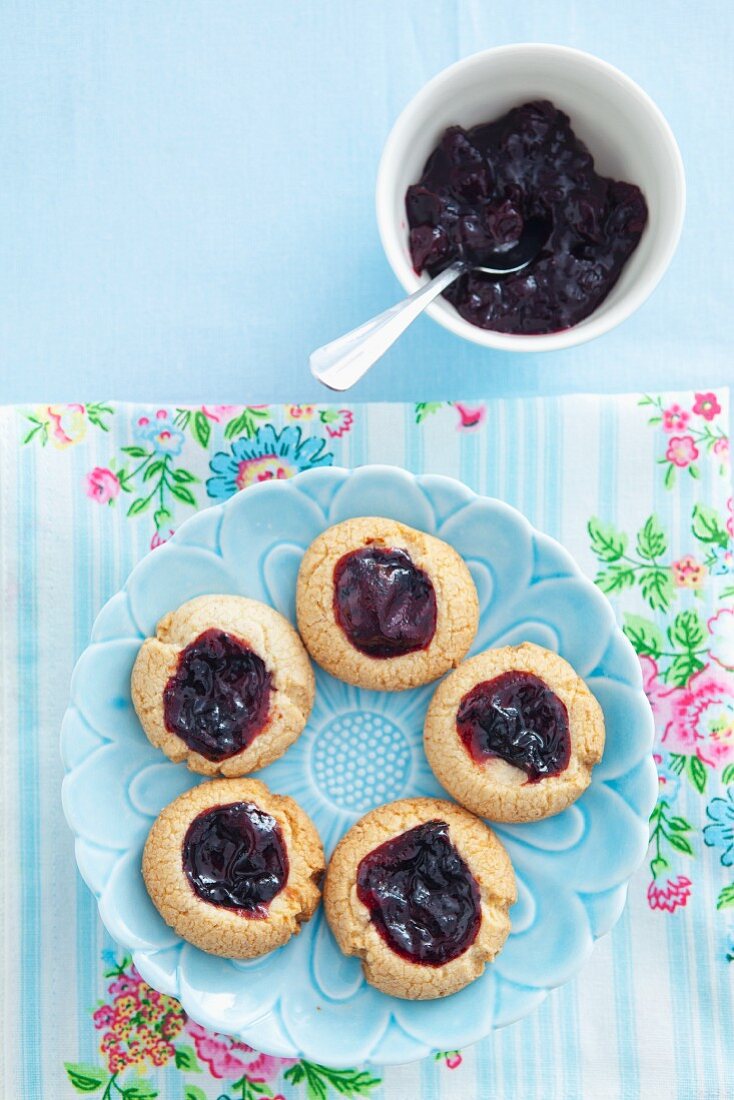 Plätzchen mit schwarzer Johannisbeermarmelade auf blauem Teller