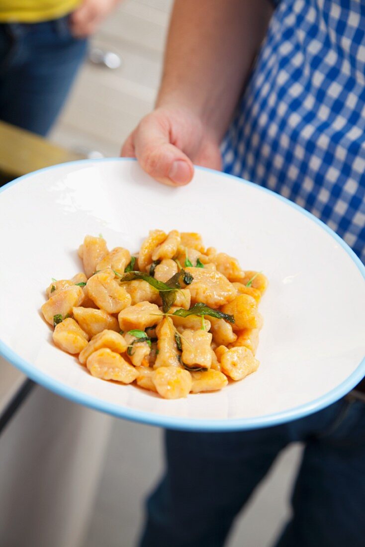 A man serving squash gnocchi with sage (Italy)