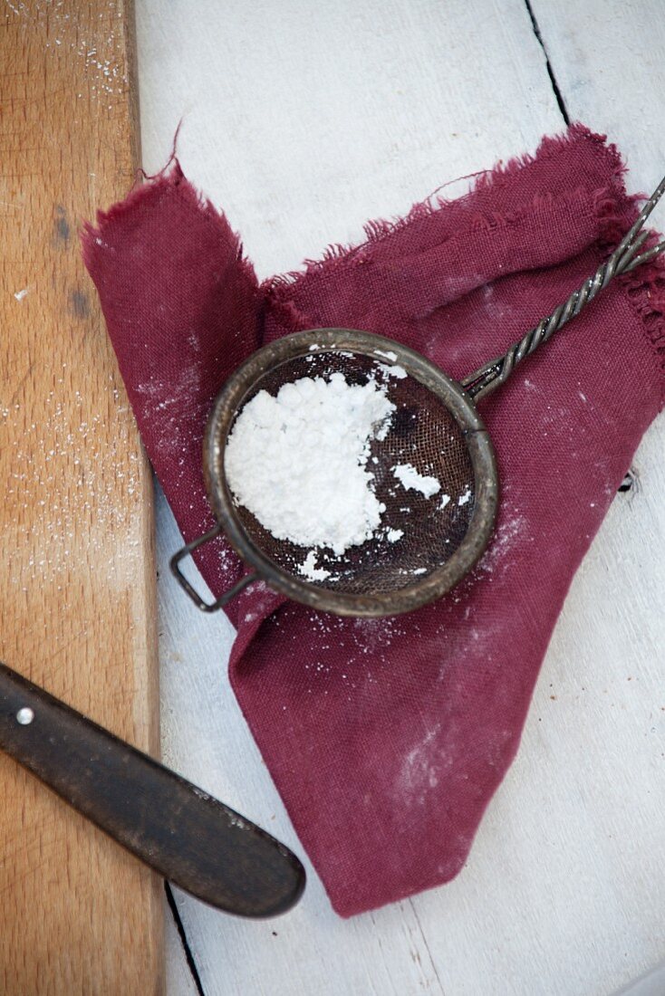 Icing sugar in an old sieve on a cloth