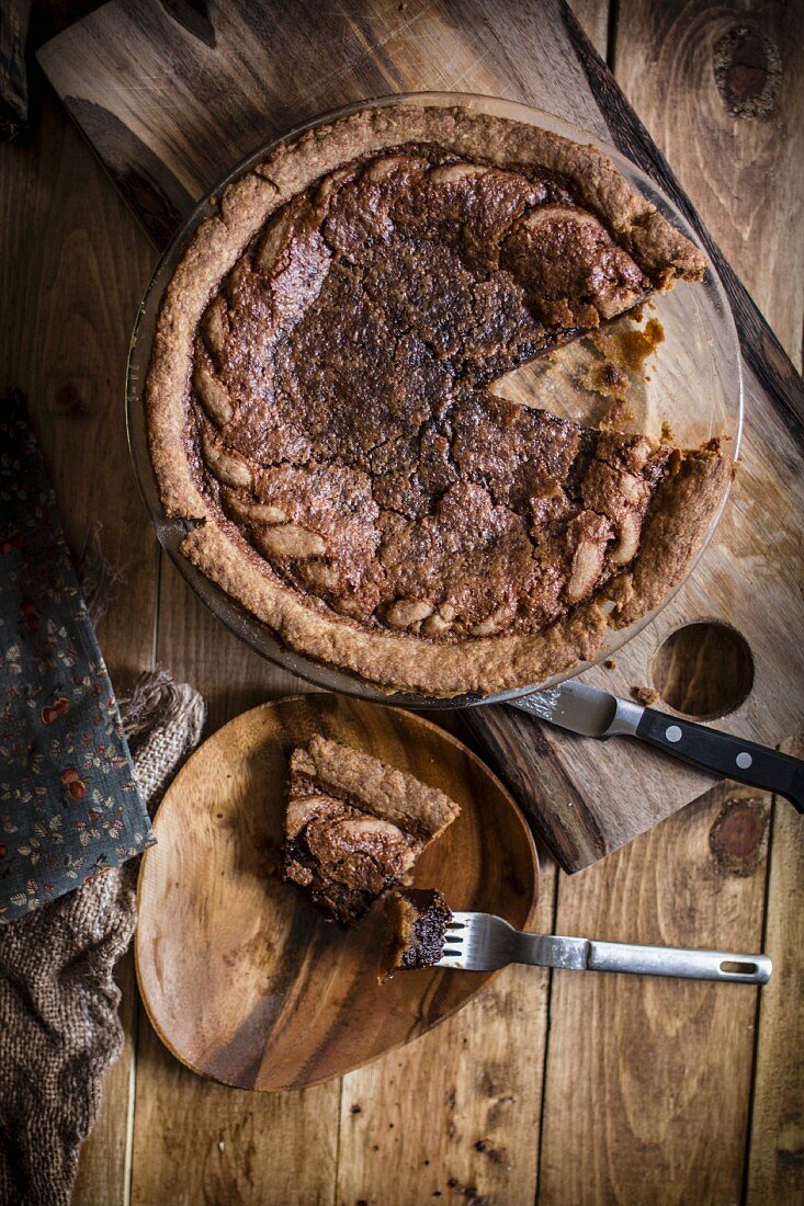 Chocolate Chess Pie with a Slice Removed; Piece of a Wooden Dish with Bite Taken Out