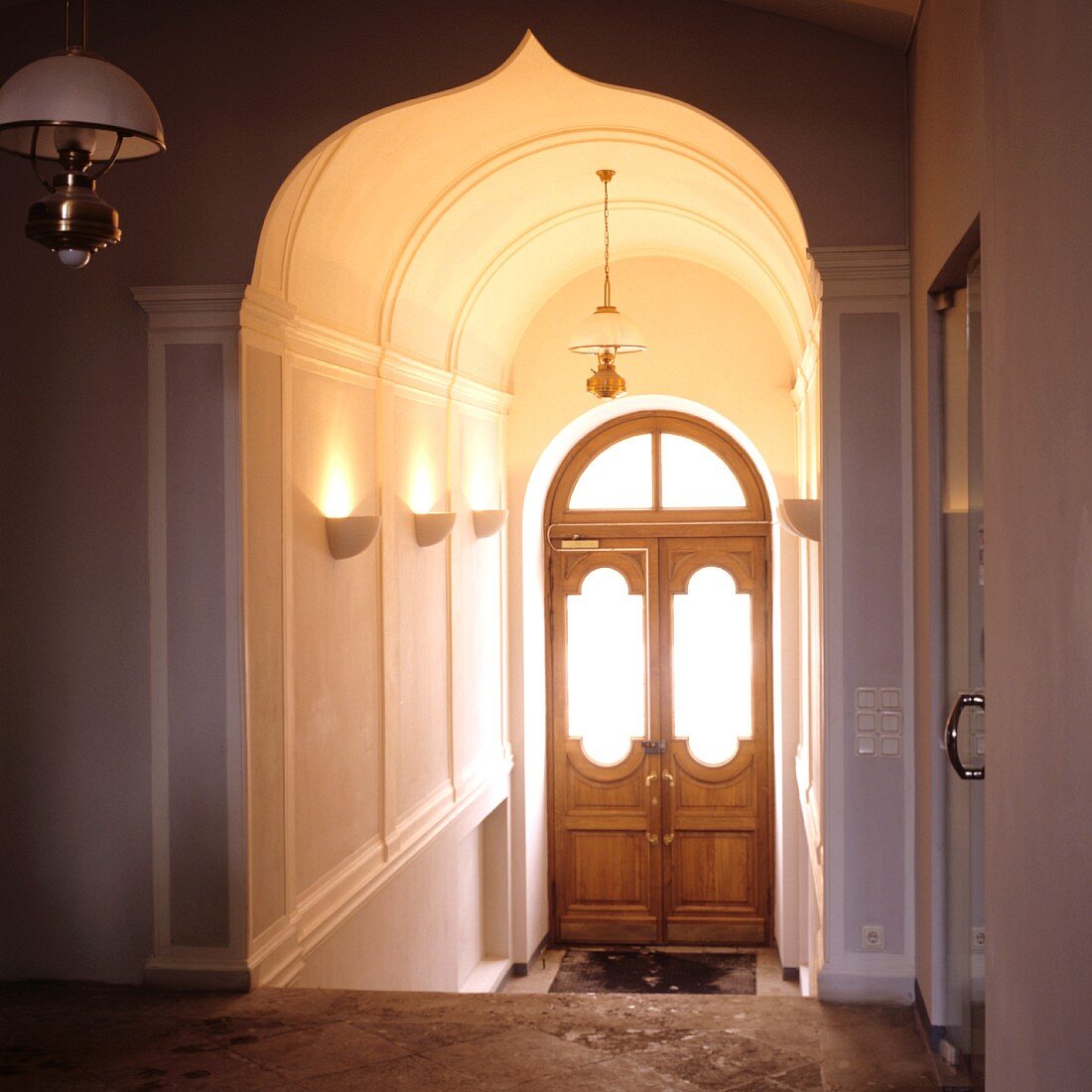 Elegant stairwell with Oriental archway and view of wooden front door