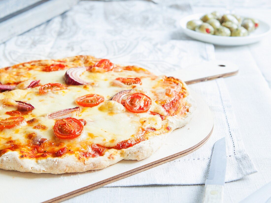 Vegetarian stone-baked pizza topped with tomatoes and red onions