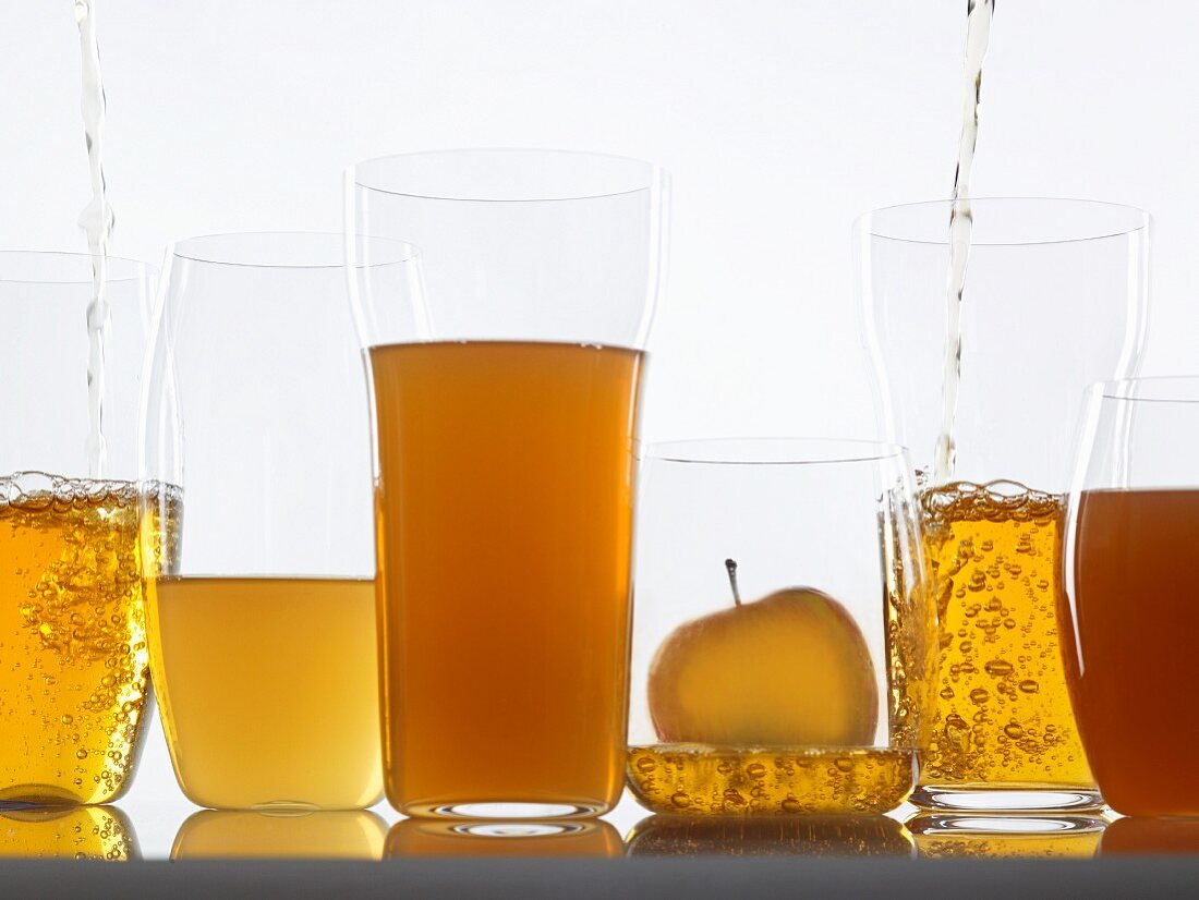 Assorted clear and cloudy apple juices in glasses