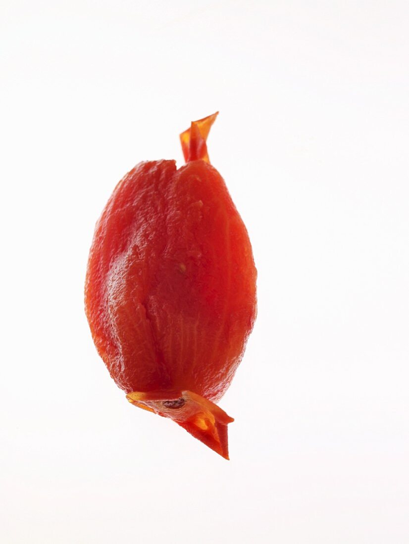 A tinned tomato without skin against a white background