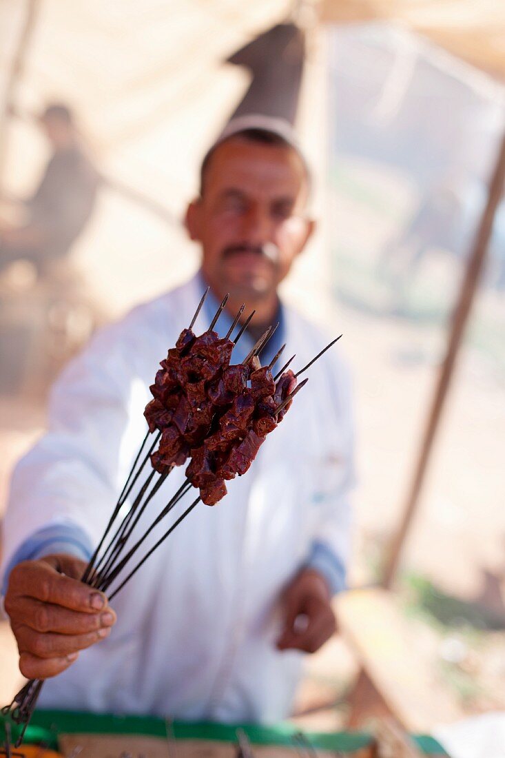 Verkäufer zeigt Grillspiesse auf einem Markt (Nordafrika)