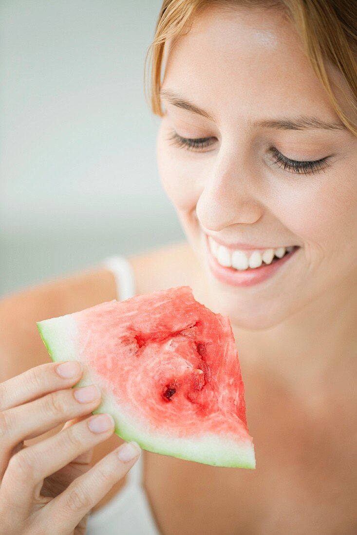 Junge Frau hält ein Stück Wassermelone