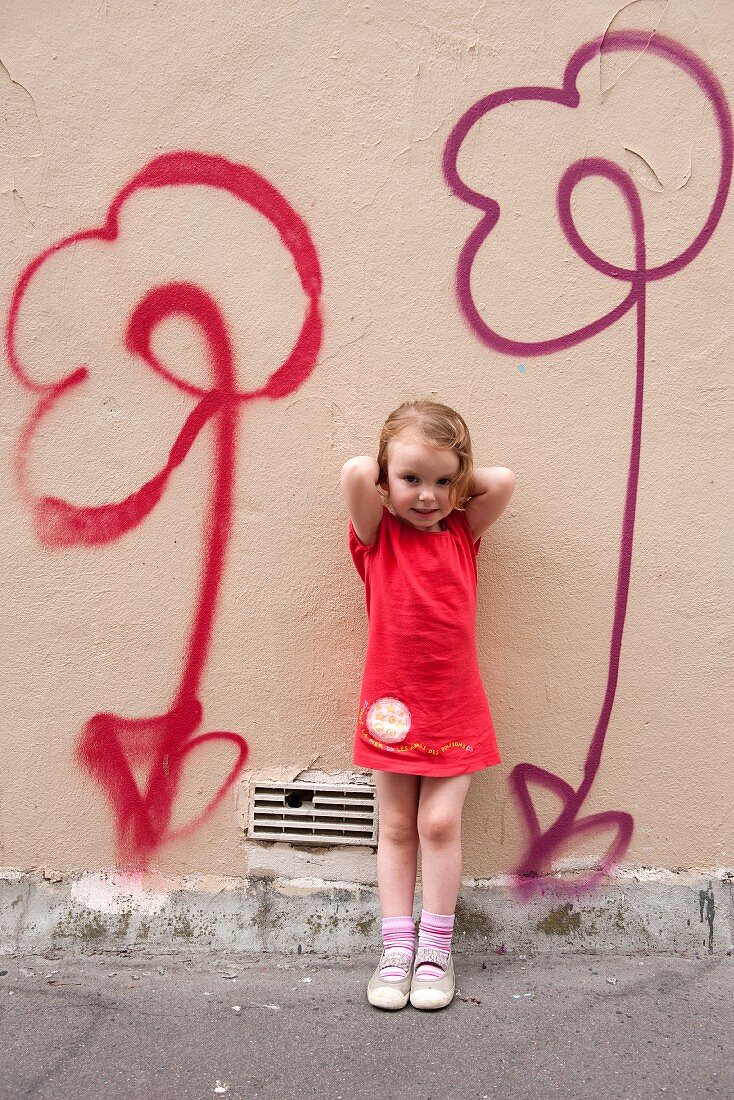 Little girl standing in front of flower motifs spray-painted on wall