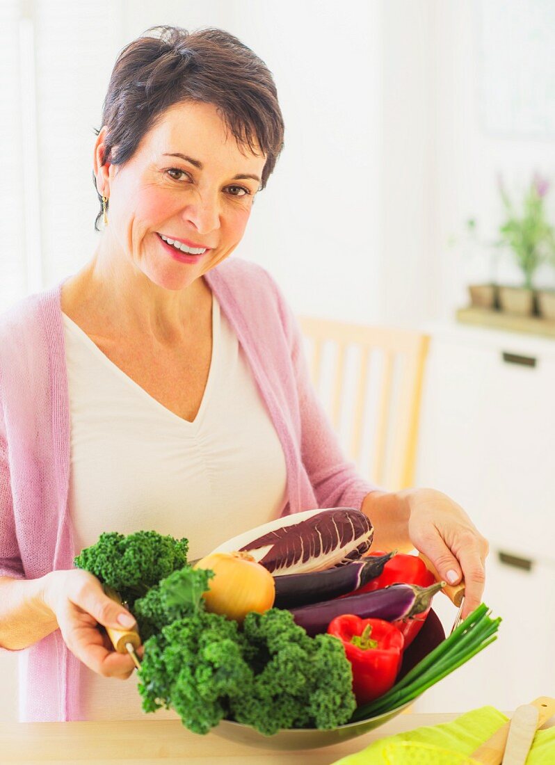 Woman with fresh vegetables in kitchen