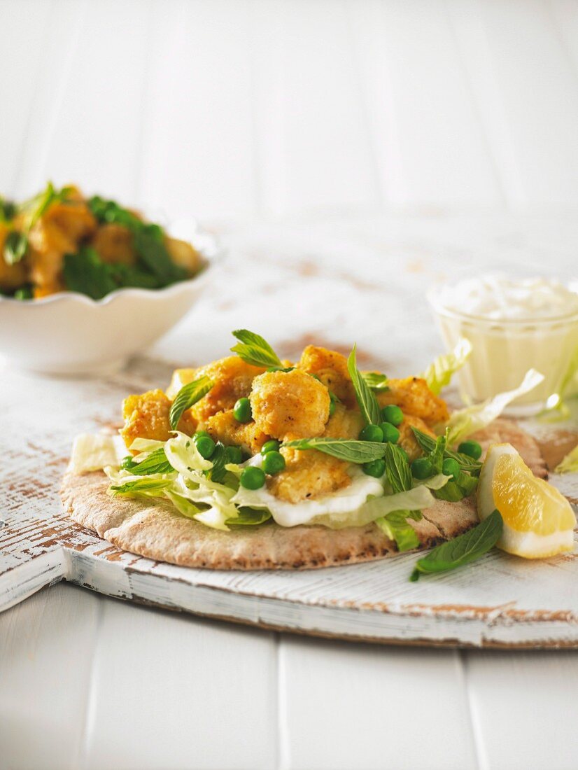 Fish nuggets with yoghurt, peas and mint, on a pita bread