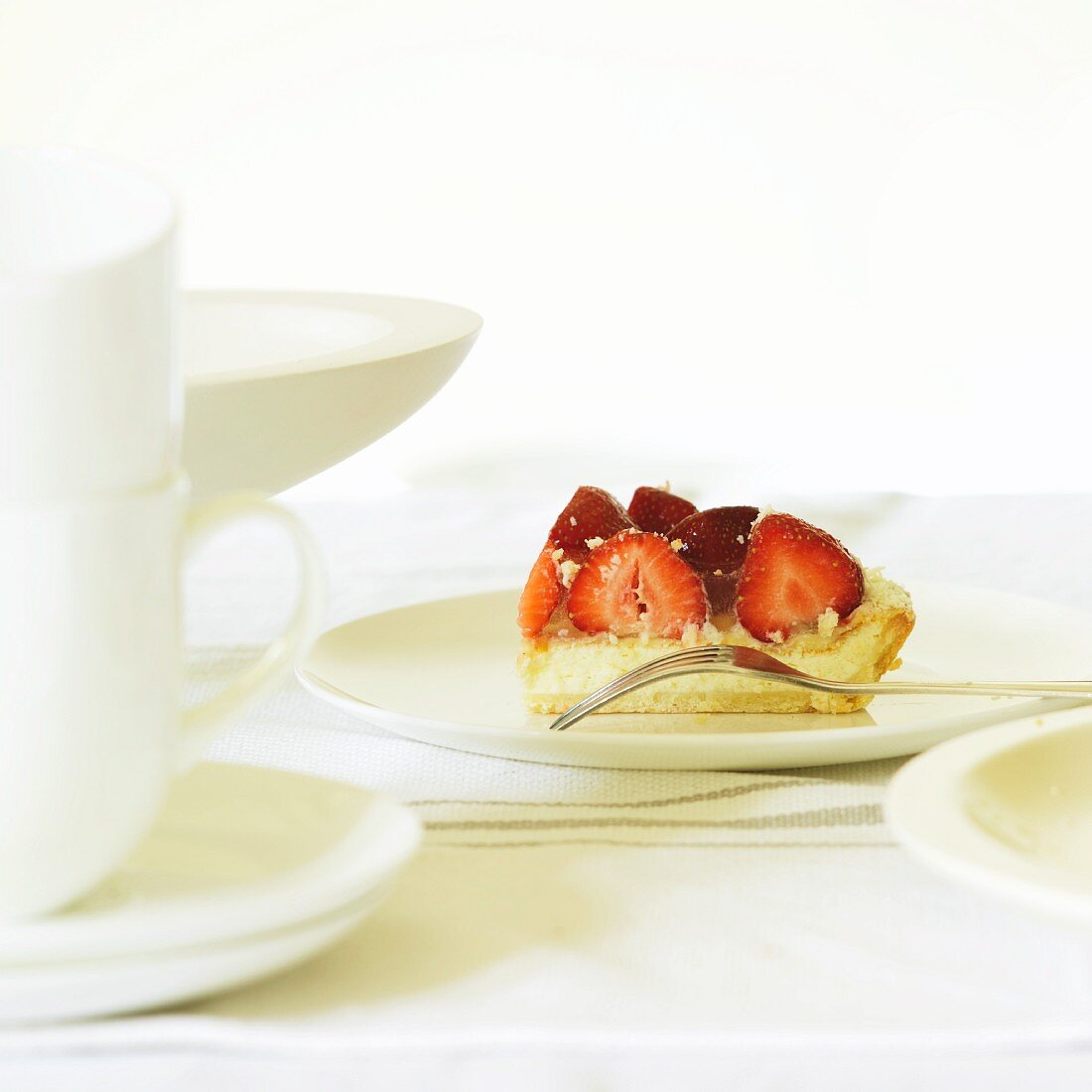 A slice of strawberry tart on a cake plate with a fork