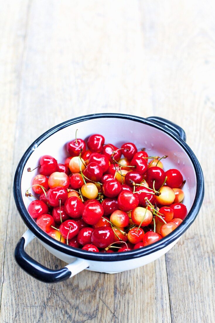 Sweet cherries in colander on a wooden table