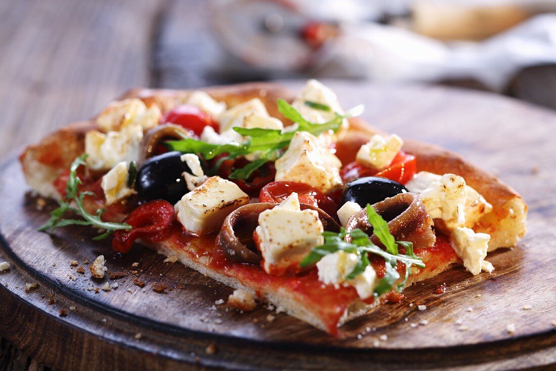 Zwei Pizzastücke mit Oliven, Feta und Anchovis