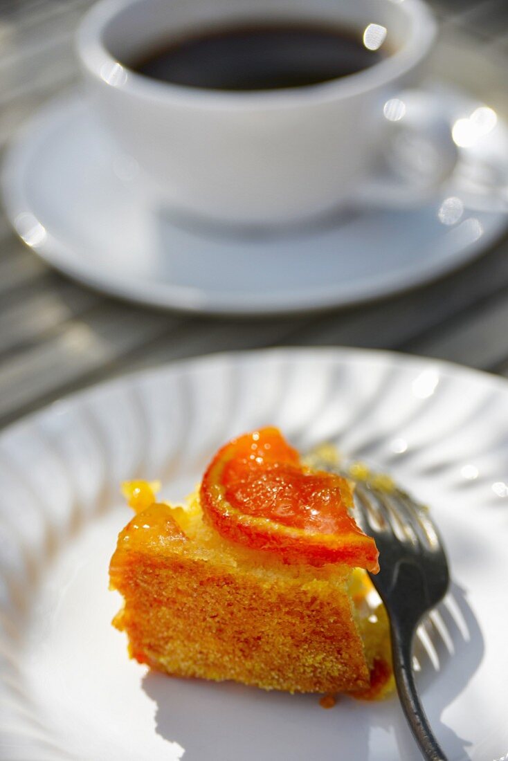 A slice of orange cake with a cup of coffee