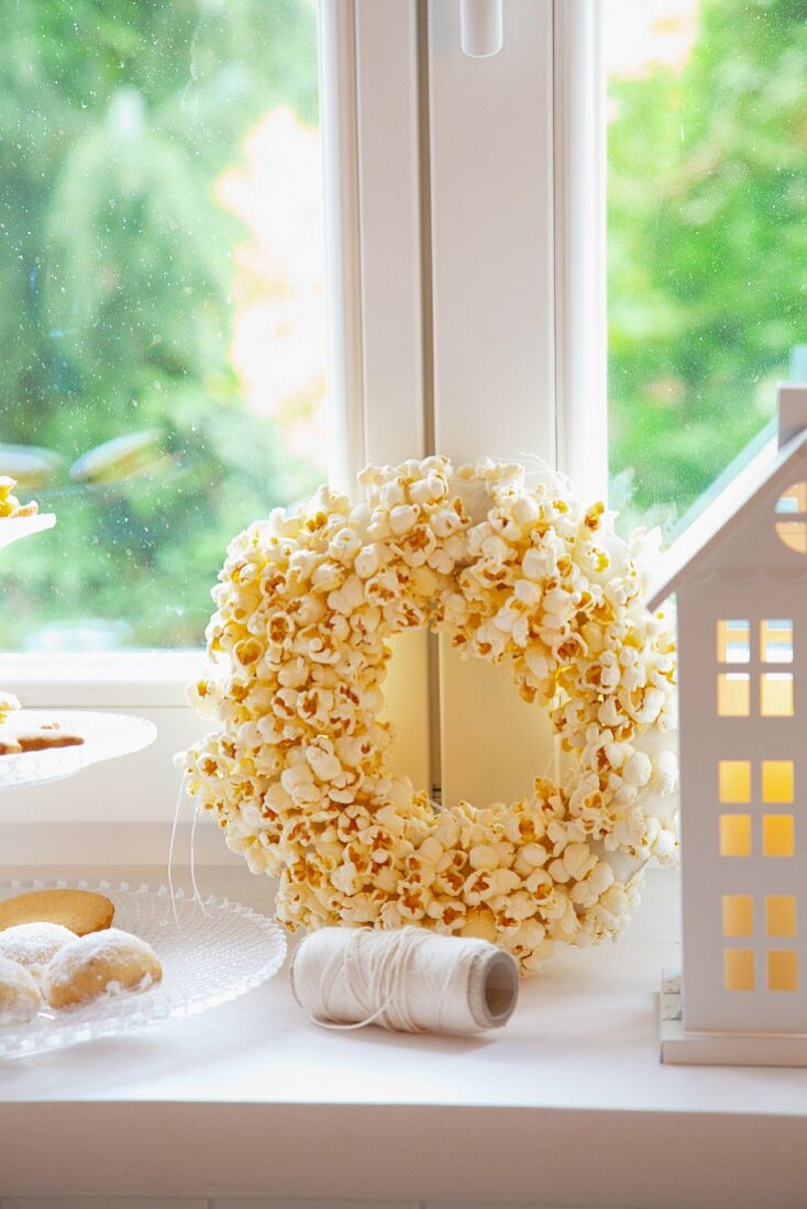 A house-shaped candle lantern, a popcorn wreath and a tiered cake stand of biscuits