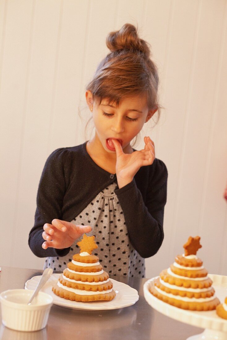 A girl decorating Christmas trees made from stacked Lebkuchen (spiced soft gingerbread from Germany)