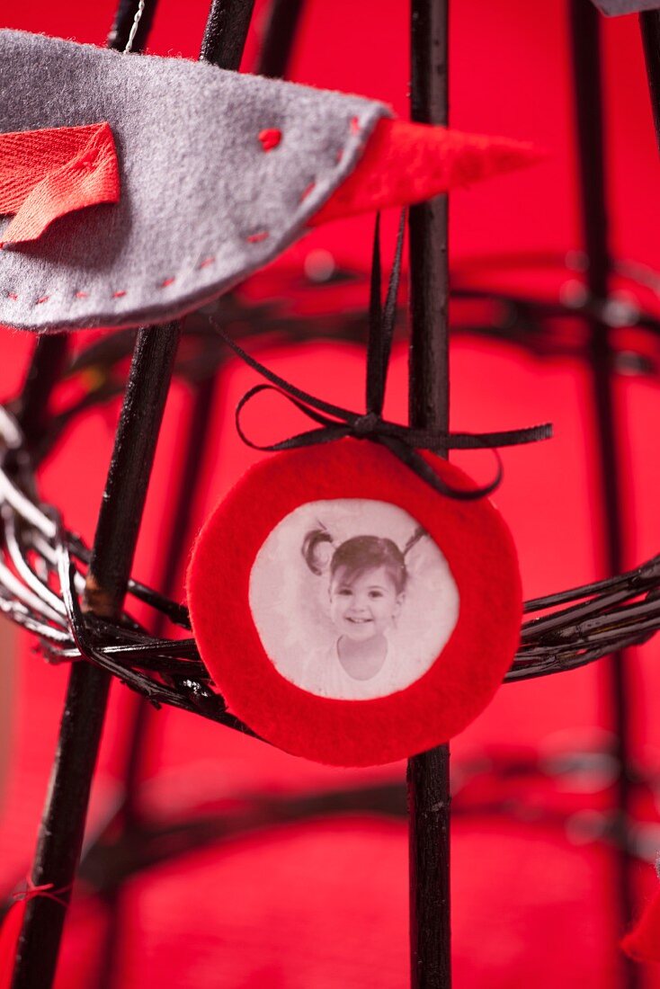 Photo of child and felt decoration on modern Christmas tree made of black-painted twigs