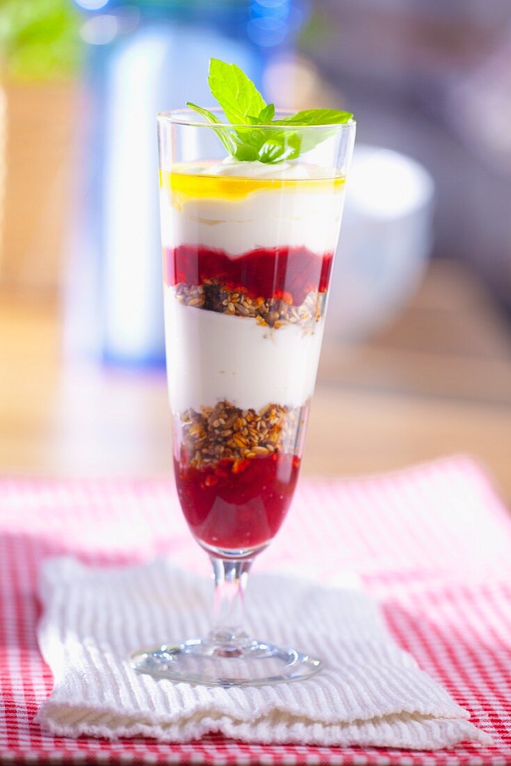 A layered dessert with raspberry jam, cereals, yoghurt and lemon juice