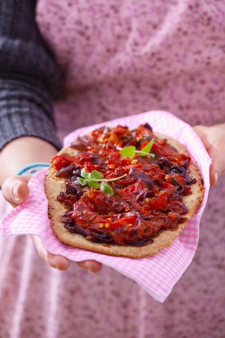 Frau hält Vollkornpizza mit Paprikaschoten und Zwiebeln