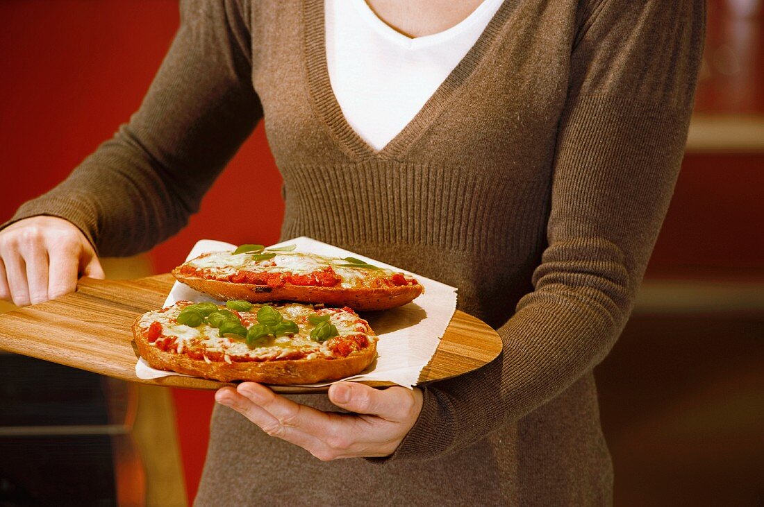 Frau serviert kleine Pizzen auf Holzschaufel