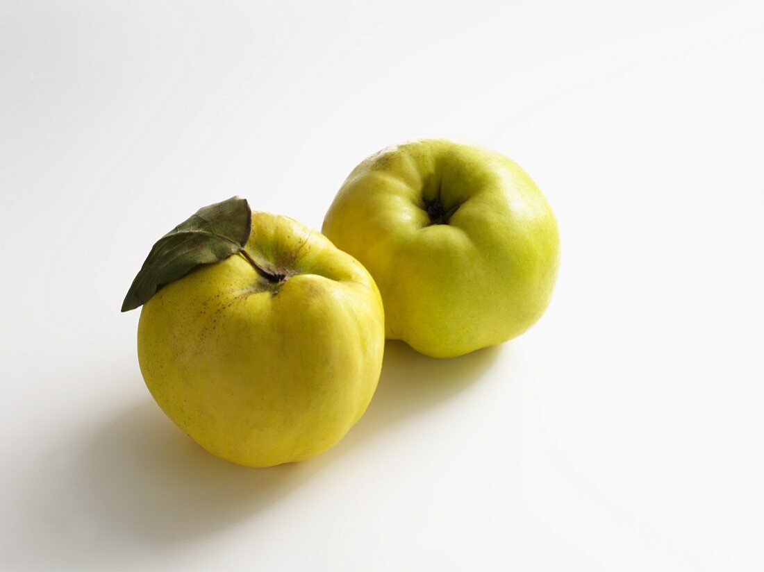 Two quinces on a white surface