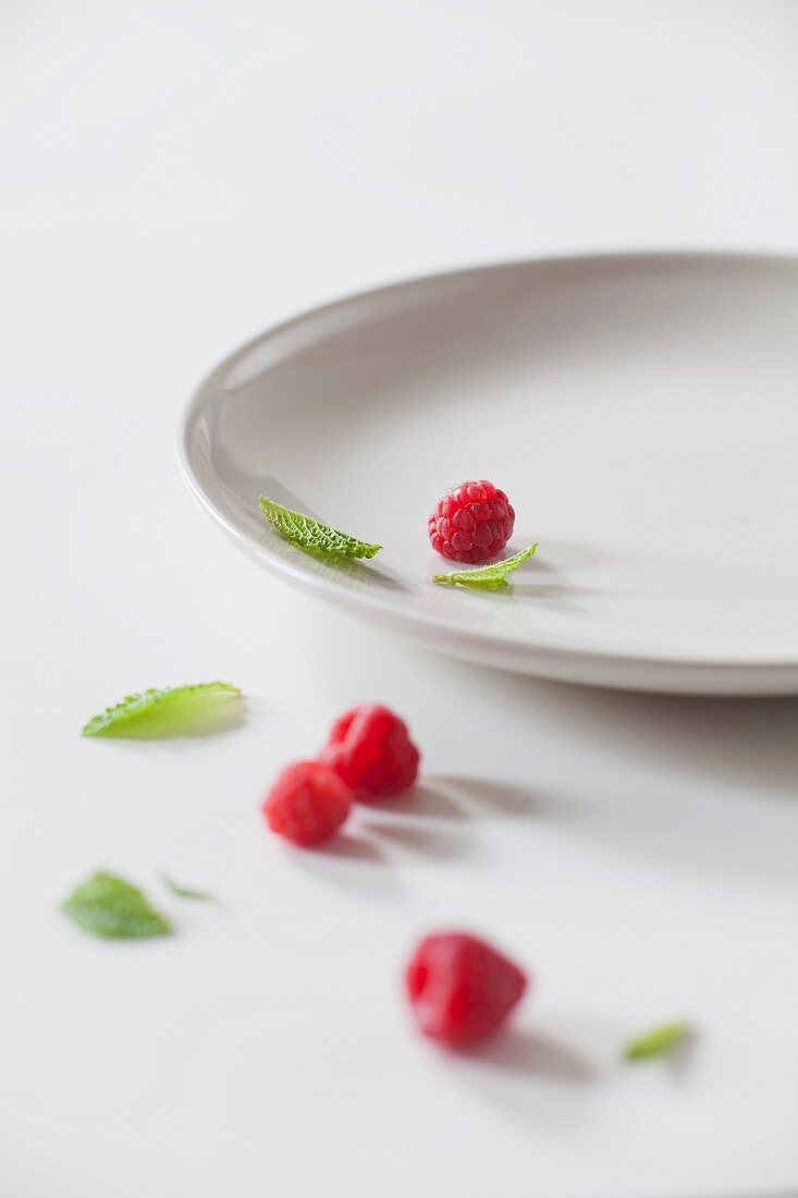 Fresh Raspberries and Mint Leaves on a White Plate