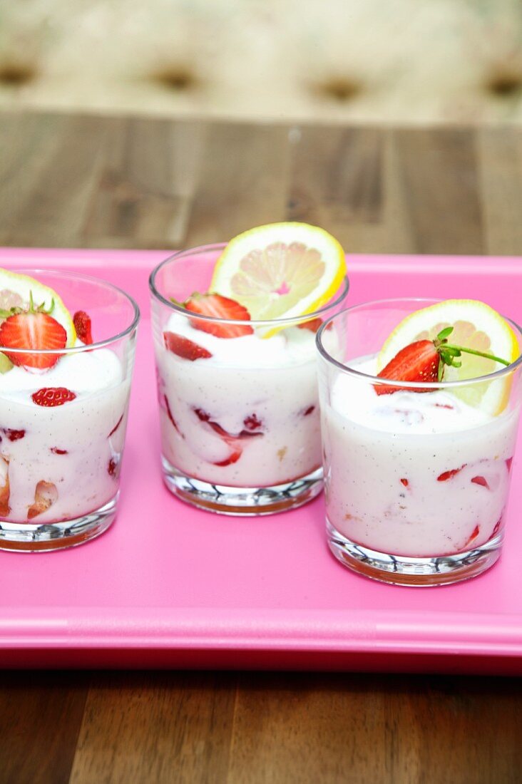 Yoghurt with fresh strawberries in dessert glasses on a tray